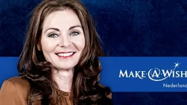 Persoon in bruin met Make-A-Wish Nederland logo op blauwe achtergrond.
