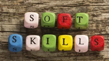 Blokken met letters vormen de woorden 'soft skills' op houten achtergrond.