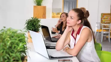 Twee personen werken aan laptops in een modern kantoor.