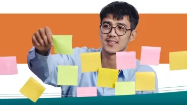 Persoon met bril kijkt naar gekleurde Post-its op glaswand.