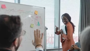 Presentatie van vrouw bij whiteboard met notities en grafieken.