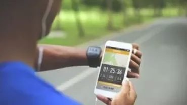 Person checks fitness data on phone while jogging in the park.