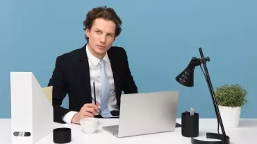 Persoon in pak werkt aan bureau met laptop en koffie