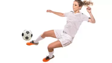 Soccer player in white kicking a ball mid-air.