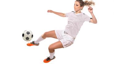 Soccer player in white kicking a ball mid-air.