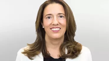 Professional portrait of a person smiling in a white coat.