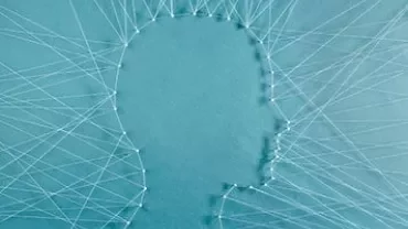 Silhouette of a head outlined with threads and pins on a blue background.
