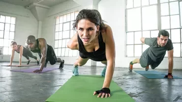 A group of people doing push-ups on mats in a gym.