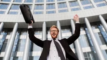 Person celebrating outside a modern building with a briefcase.