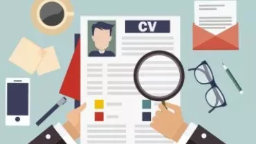 A person examining a resume with a magnifying glass, surrounded by a phone and glasses.