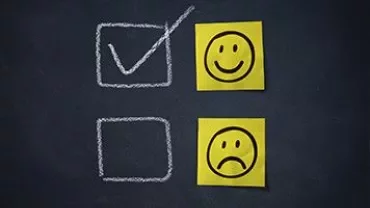Twee emoji gezichten naast selectievakjes op schoolbord