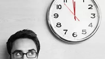 Person looking up at a clock showing almost 3 o'clock.