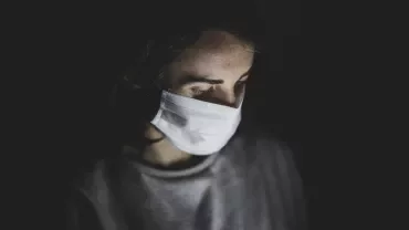Person wearing a face mask in dim light.