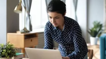Persoon werkt op laptop in een moderne, lichte kamer.