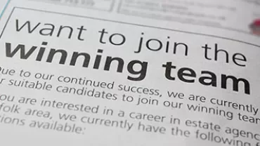 Close-up of a newspaper ad asking for candidates to join a winning team.