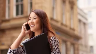 Person smiling while talking on a phone outside.