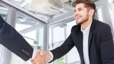 Two people shaking hands in a modern office setting.
