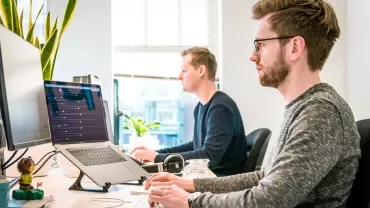 Two people working at computers in an office.