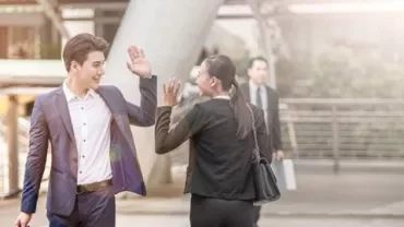 Two businesspersons greeting each other with a high five outdoors.