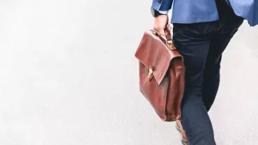 Person holding a brown briefcase walking