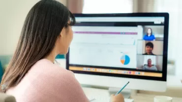 Person working on computer with charts and video call.