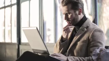 Persoon denkt na terwijl ze op een laptop werken.