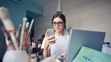 Person using a laptop and looking at a phone.