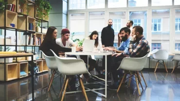 A group of people collaborating on laptops in an office.