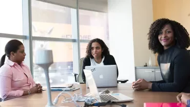 People having a meeting around a table with laptops.