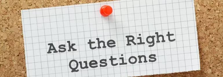 Note on corkboard reading 'Ask the Right Questions' with a pushpin.