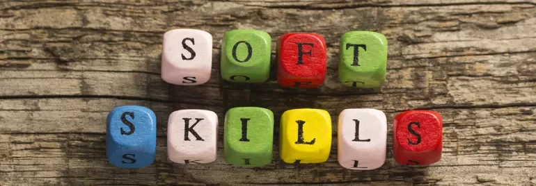 Colorful blocks spell 'soft skills' on a wooden surface.