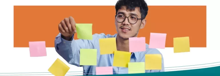 Persoon met bril kijkt naar gekleurde Post-its op glaswand.