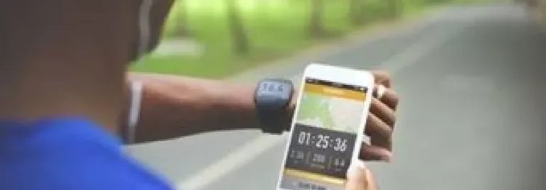 Person checks fitness data on phone while jogging in the park.