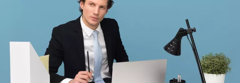 Persoon in pak werkt aan bureau met laptop en koffie