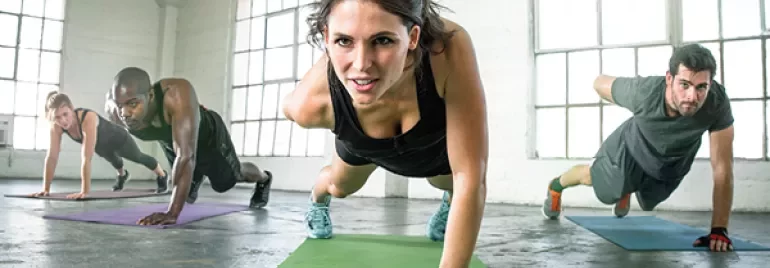 A group of people doing push-ups on mats in a gym.