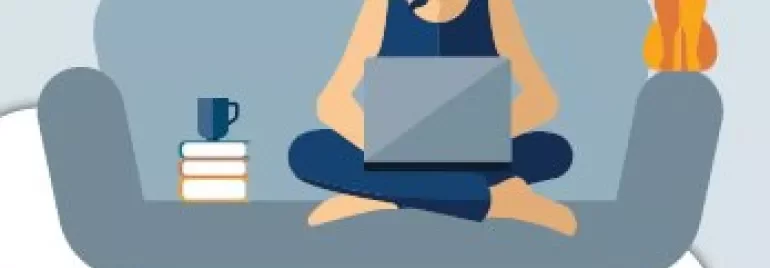 Person sitting on a couch with a laptop, books, a cup, and a cat.