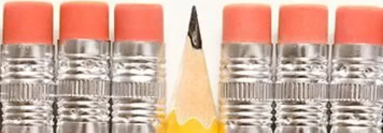 Seven pencils standing upright, one is sharpened.