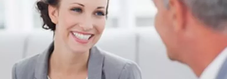 Two people engaged in a conversation, smiling in an office setting.