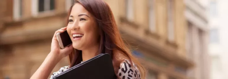 Person smiling while talking on a phone outside.
