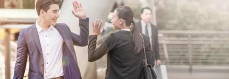 Twee zakenmensen die elkaar buiten begroeten met een high five.