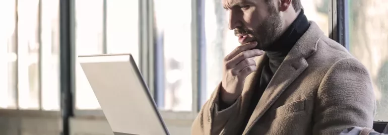 Individual thinking while working on a laptop.