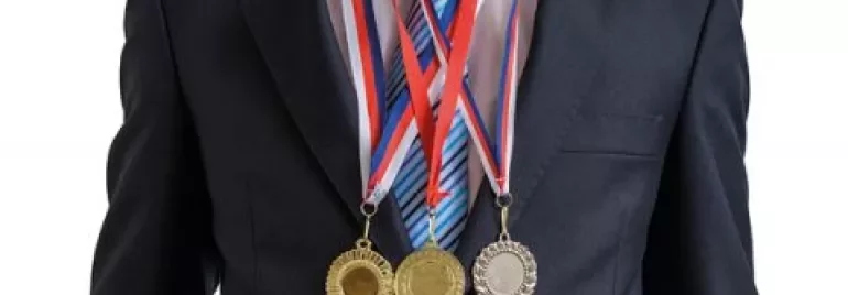 Person in a suit wearing three medals around the neck.