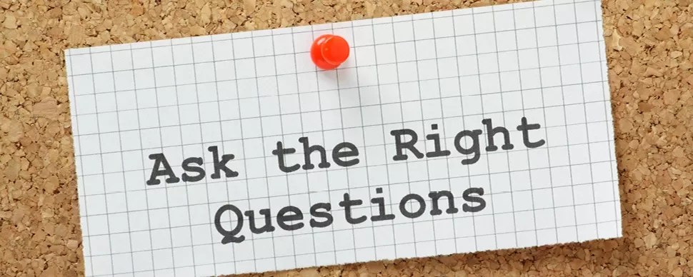 Note on corkboard reading 'Ask the Right Questions' with a pushpin.