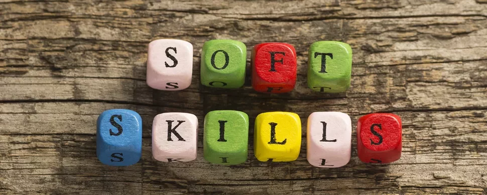 Colorful blocks spell 'soft skills' on a wooden surface.