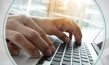Twee handen typen op een laptoptoetsenbord bij daglicht.