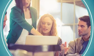 Group collaborates around a laptop in an office setting.