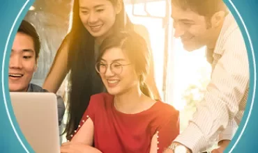 A group of people smiling and looking at a laptop together.