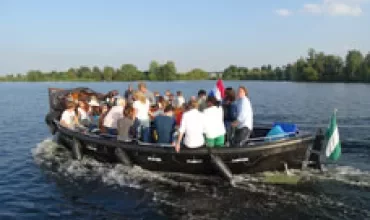 Groep mensen op een boot varend over het water bij zonnig weer.